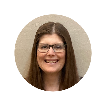 Smiling woman with long brown hair and glasses, against a plain background.